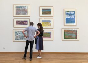 Besucher schauen die Bilder von Laura Jo Pierce an