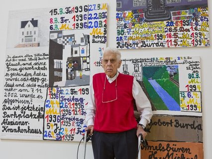 Künstler Robert Burda steht mit seinen Arbeiten bei der Ausstellungseröffnung 